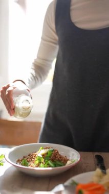 Güzel, güneşli bir mutfakta, kendini adamış bir şef, yeni hazırlanmış bir yemeğin üzerine aromalı tatlar serpiştirir.