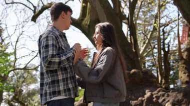 Genç bir çift açık havada hassas ve sevecen bir anı paylaşıyor. Doğaları gereği güzel manzaralarla çevrili.