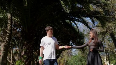 Sevimli bir çift, uzun palmiye ağaçlarıyla çevrili canlı bir açık havada hassas ve iç açıcı bir anın tadını çıkarır.