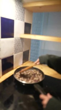 Bir insan, sıcak bir mutfakta, bir tencerede lezzetli bir yemek pişiriyor ve yemek pişirme becerilerini sergiliyor.