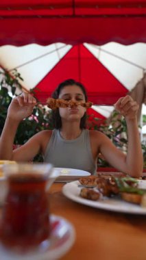 Hevesli bir yemek aşığı, canlı ve canlı bir yemek atmosferinde lezzetli ızgara şişler yemekten zevk alır.