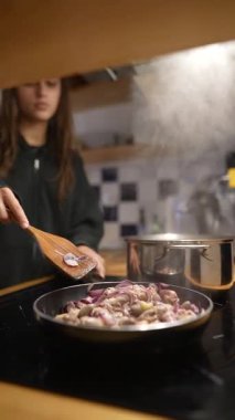 Genç bir birey modern bir mutfakta lezzetli yemekler pişirir. Mutfak yetenekleri ve taze malzemeler sergiler..