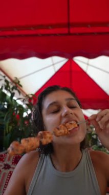 Heyecanla dolu canlı bir açık hava yemek atmosferinde şişin tadını çıkaran bir kadın.