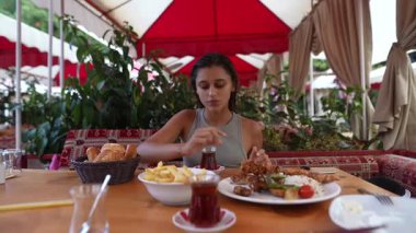 Etrafı yemyeşil ve canlı renklerle çevriliyken, doyurucu bir yemeğin tadını çıkaran bir kadın.