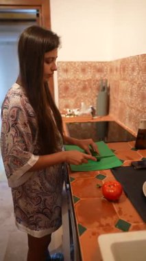 Şık bir mutfakta, bir kadın çeşitli taze, renkli sebzeler hazırlar, aşçılık yeteneklerini sergiler.