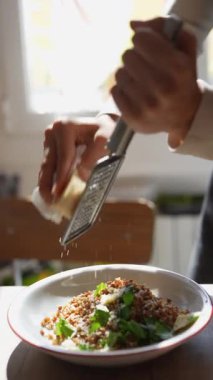 Yetenekli bir aşçı lezzetli bir tabağı lezzet profilini geliştirmek için taze rendelenmiş peynirle süslüyor.