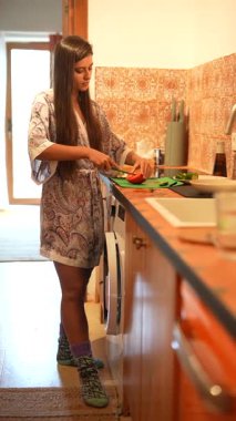 Genç bir kadın, rahat bir mutfak ortamında rahat bir bornoz giyerken yemek pişirmekten hoşlanır.