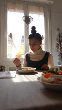 Bir kadın sıcak, sıcak ve güneşli bir mutfak ortamında lezzetli ve besleyici bir yemeğin tadını çıkarmak için zaman harcar.