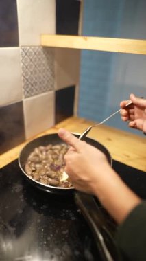 Tavada sotelenen mantarlara tereyağı ekleyen bir el, aşçılık meraklıları için mükemmel.