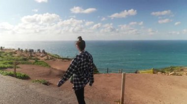 Güzel bir okyanus zeminine karşı kıyı yolunda gezinen bir kadının yer aldığı manzara..