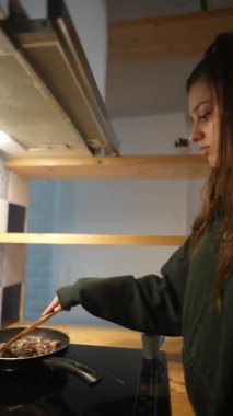 Genç bir insan rahat bir mutfak ortamında ustalıkla yemek pişiriyor, çağdaş mutfak becerilerini sergiliyor..