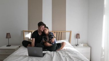 Sevgi dolu bir ebeveyn ve çocuğun dizüstü bilgisayarla keyifli bir şekilde vakit geçirdiği iç açıcı bir sahne.