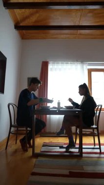 Huzurlu ve huzurlu bir sahnede iki kişi sıcak bir yemek masasında keyifli bir yemek yiyor ve eğleniyor.