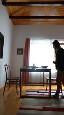 Bir yemek masası, iki kişi ve doğal ışığın pencereden içeri aktığı rahat bir ortam..