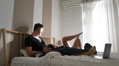 Genç bir adam boş zamanlarını yatakta geçirir. Cihazına dalmışken yumuşak doğal ışıkta rahatlar.