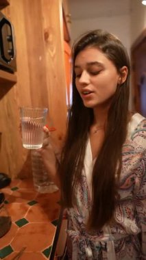 Bir kadın sıcak bir mutfak ortamında lezzetli yemekler hazırlarken ferahlatıcı sudan zevk alır.