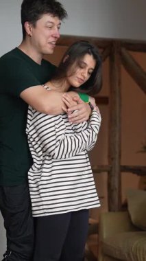 Bir çift sıcak ve sevgi dolu bir kucaklaşmayı paylaşıyor, derin sevgilerini sıcak ve sıcak bir evde sergiliyorlar.