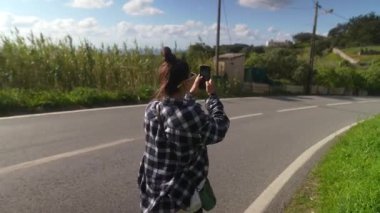 Bir kadın güzel bir şekilde doğanın özünü yakalar ve nefes kesici manzaralı bir yolda sakin bir şekilde yürür.