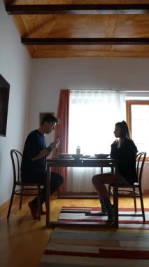 İki yakın arkadaş birlikte lezzetli bir yemek yiyorlar, sıcak ve samimi bir yemek masasının sıcaklığını ve bağlantısını yakalıyorlar.