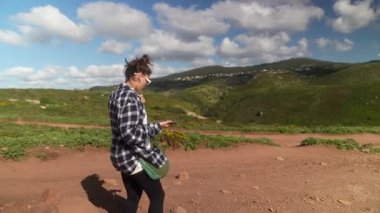 Sıradan giyinmiş bir kadın, gür tepeler ve manzarayla çevrili, canlı bir açık hava manzarasından hoşlanır..