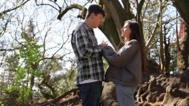 Sevgi dolu bir çift, güzel, huzurlu bir orman ortamında el ele tutuşurken hassas ve samimi bir anın tadını çıkarır.