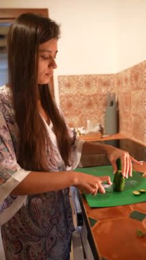 Samimi bir mutfakta, yetenekli bir kadın tezgahın üstünde taze sebzeleri kolaylıkla keser.