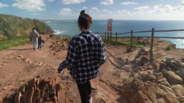 Neşeli bir arkadaş grubu güneşli bir günde güzel bir sahil yolu boyunca güzel bir yürüyüş yapar.