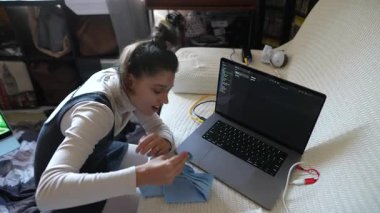 Odaklanmış ve hırslı genç bir kadın rahat bir ev ortamında çalışırken tamamen laptopuyla meşgul oluyor.