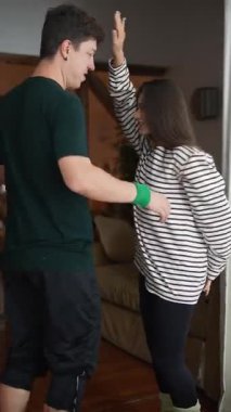 Bir çift, oturma odalarının sıcak ve davetkar atmosferinde birlikte eğlenceli ve canlı bir dansın tadını çıkarıyor.