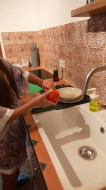 Genç bir kadın, sıcacık mutfak ortamında bir dizi taze, canlı sebze hazırlıyor.