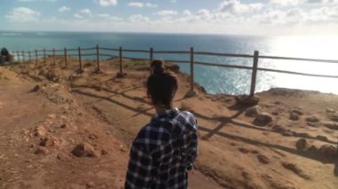 Bir insan muhteşem bir okyanus manzarasına tepeden bakar. Huzuru ve güzelliği yakalar..