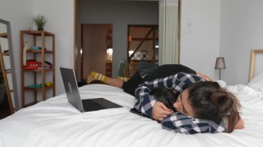 İki birey, yakınlarda bir dizüstü bilgisayarla yatakta samimi bir anı paylaşıyor ve bağlantılarını açıkça aktarıyor.