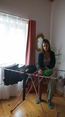 Sakin bir mekanda, genç bir kadın çamaşırlarını kurutma sehpasında ustalıkla yıkar.