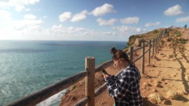 Genç bir kadın nefes kesen okyanus manzarasını yakalar ve açık havada güneşli güzel bir günün tadını çıkarır.