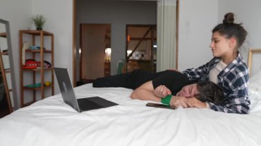 Bir çift, rahat bir yatakta keyifle vakit geçirir. Kahkahalarını ve rahatlatıcı rahatlığını paylaşır.