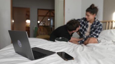 Genç bir çift, sıcak bir yatak odası ortamında birbirlerini kucaklayarak, birlikte eğlenceli ve hassas anlar geçiriyorlar.