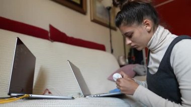 İki ayrı dizüstü bilgisayarda ustalıkla odaklanmış bir birey, modern uzaktan çalışma dinamikleri sergiliyor.