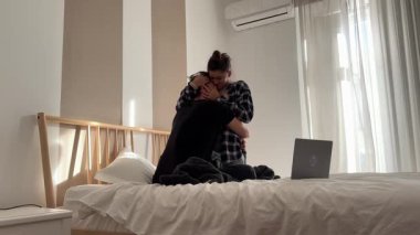 Genç bir çift yatakta hassas bir anı paylaşıyor. Sabah ışığı huzurlu bir atmosfer yaratıyor.