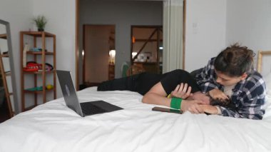 Bir çift, rahat yataklarında dizüstü bilgisayarlarını kullanarak, sevgiyi, samimiyeti ve rahatlığı birlikte paylaşırlar.