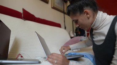 Konforlu bir ev ortamında, bir kadın dizüstü bilgisayar görevleriyle yakından ilgilenir, modern uzaktan kumandalı çalışmalara örnek olur.