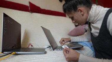 Bir kadın işine derinden bağlıdır, iki dizüstünde etkili bir şekilde birden fazla iş yapar, uzaktan üretkenliğini gösterir.