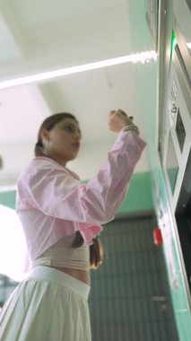 Tarz sahibi bir kadın, kolaylık ve moda karışımını vurgulayan modern bir otomatla etkileşim içindedir.