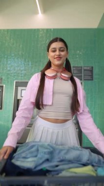 Moda ve şık bir kız çamaşırlarını zarif bir şekilde renkli ve canlı bir çamaşırhane düzenliyor.