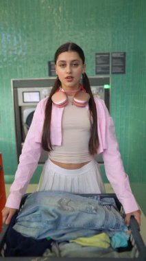 Modayı takip eden genç bir kadın, eşsiz stili ve kendine güveni ile modern bir çamaşırhanede çamaşırhaneyi ustalıkla yönetiyor.