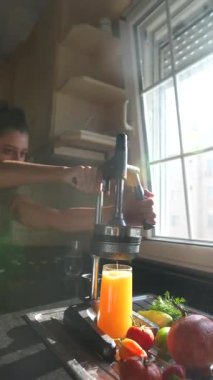 Canlı bir sahne, taze meyve ve sebzelerden lezzetli meyve sularının yapıldığı güneşli bir mutfakta sergileniyor.