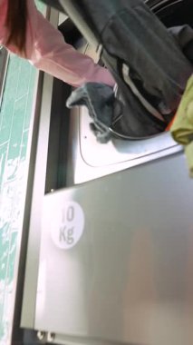 Çamaşır makinesine çamaşır yükleyen biri. İşlevsellik ve kolaylığa odaklan.