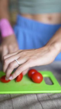 Bir kadın domatesleri ustalıkla canlı bir kesim tahtasıyla doğruyor, mutfak hazırlıklarını gösteriyor..