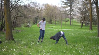 Bereketli yeşil bir parkta, iki genç yetişkin dinamik egzersizler yaparak sağlık ve uygunluklarını arttırıyorlar.
