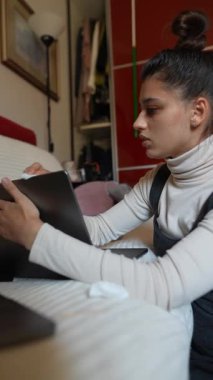 Genç bir kadın özenle dizüstü bilgisayarı üzerinde çalışıyor. Etrafı ev ortamlarıyla çevrili.