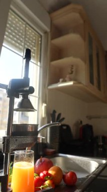 Bir insan, olgun portakallar ve domateslerden taze meyve suyu yapmak için el sıkacağı kullanmaktan mutluluk duyar.